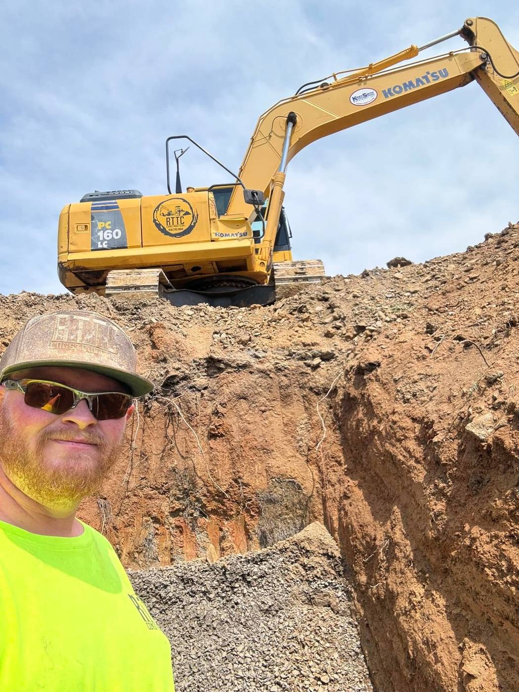 RTTC crew member with a Komatsu excavator at a deep excavation cut