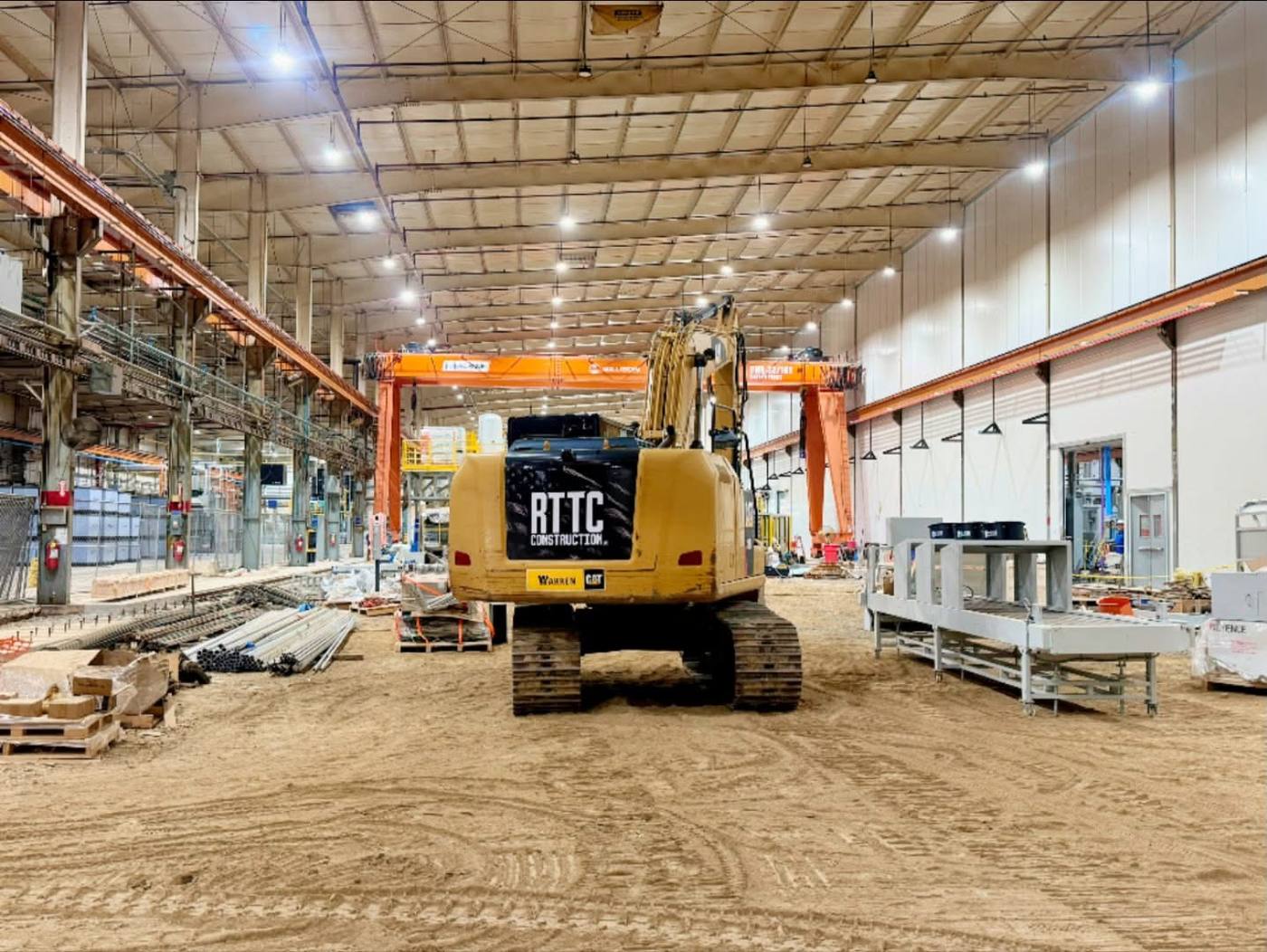 RTTC Construction excavator performing site work inside a large industrial building